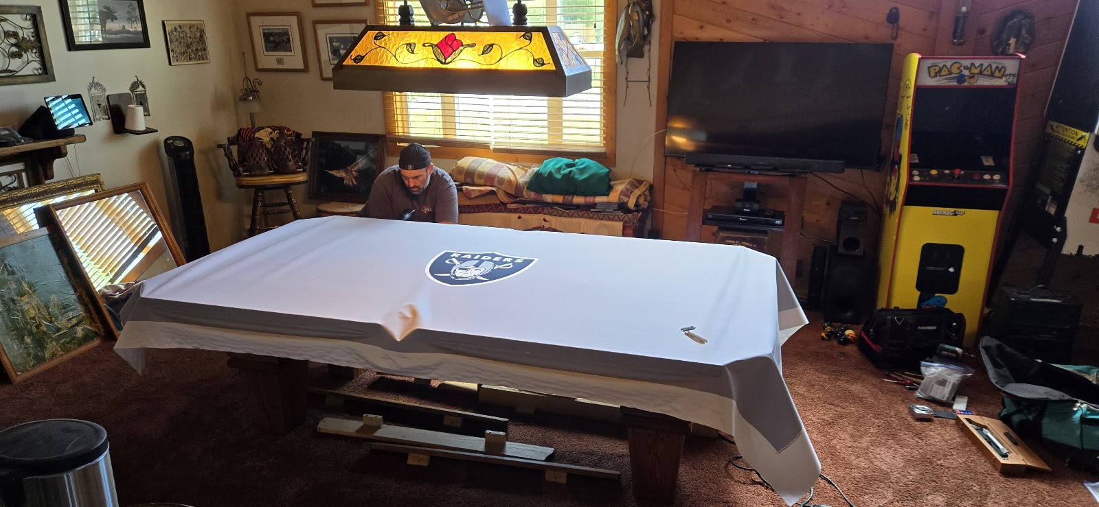 Raiders logo cloth being fitted onto a pool table mid-installation