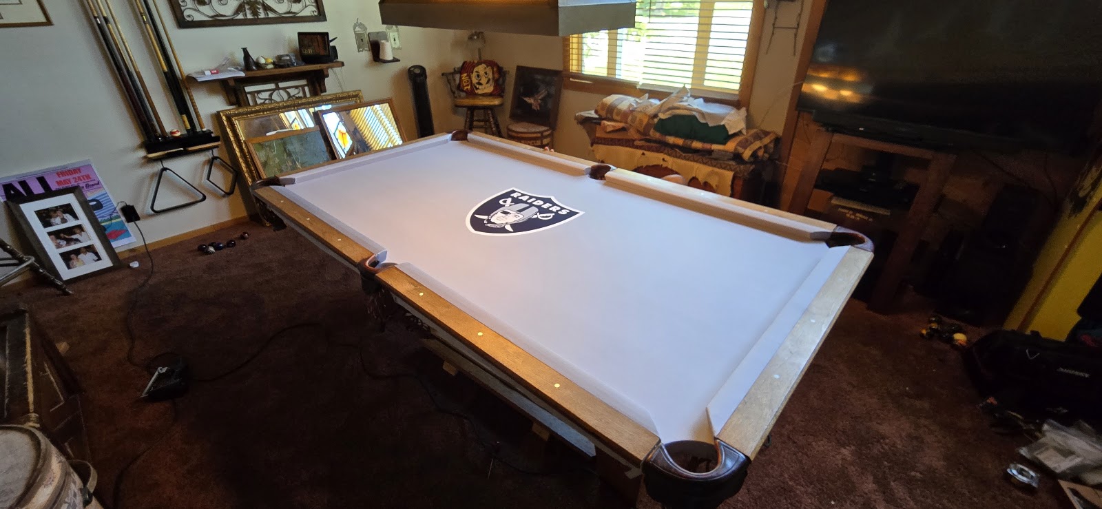 Finished pool table with custom Raiders felt in a warm game room